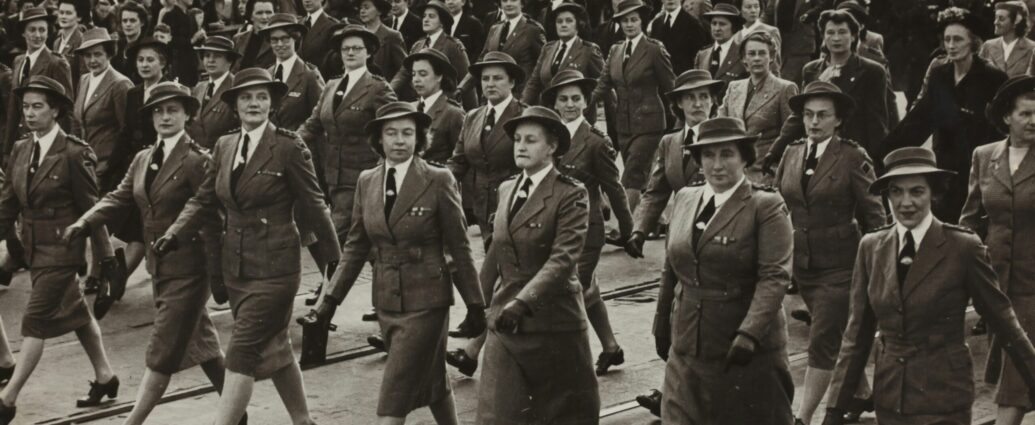 Vintage picture of women in military-like uniforms marching in a row.