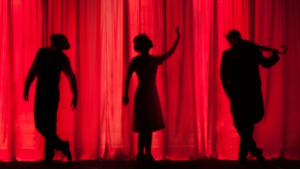 Three performers on theatre stage.